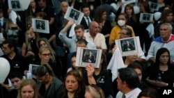 ARCHIVO - Personas, sosteniendo una imagen del difunto fiscal antidrogas Marcelo Pecci, asisten a una reunión para exigir justicia por su asesinato, en Asunción, Paraguay, el viernes 13 de mayo de 2022.
