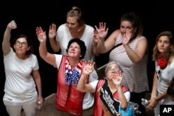 Mujeres que protestan contra las políticas de detención de familias migrantes en la frontera de la administración Trump muestran sus manos con la inscripción WE CARE (nos importa) en referencia a la chaqueta que la primera dama Melania Trump usó en su primer viaje para visitar niños migrantes detenidos en la frontera. Junio 28 de 2018.