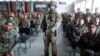 FILE - Afghan National Army soldiers attend their graduation ceremony while a NATO soldier stands guard at the Kabul Military Training Centre in Kabul, Afghanistan, Jan. 27, 2019.