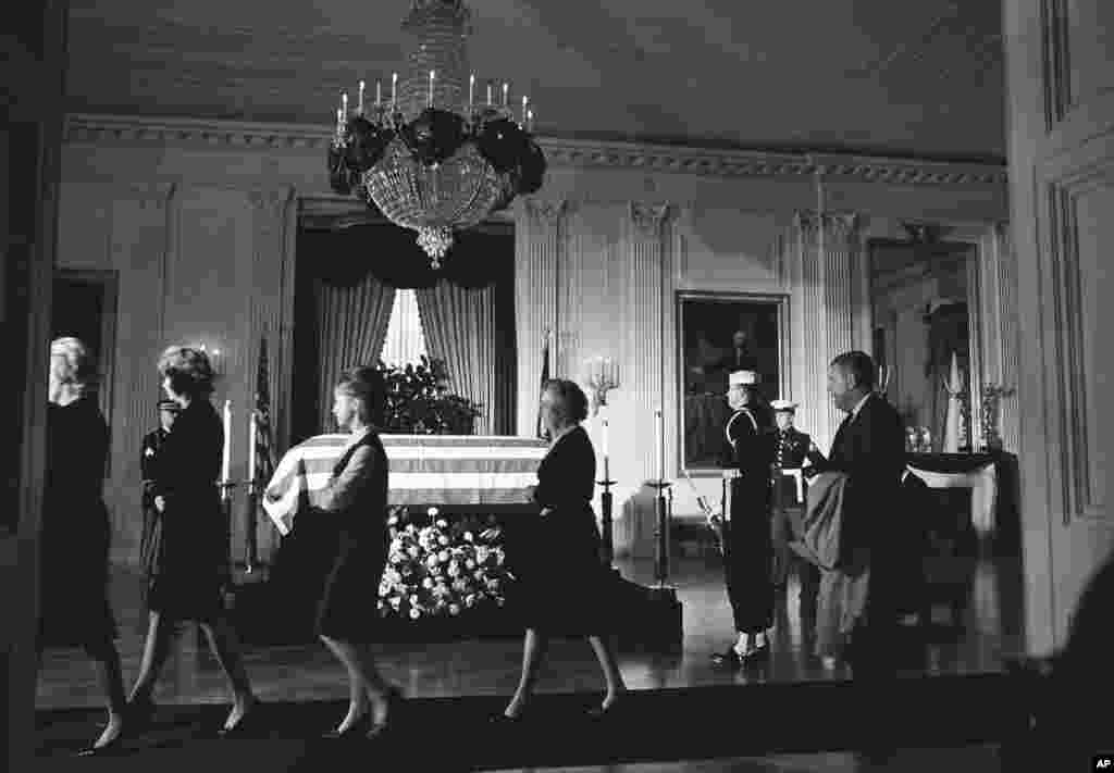 Miembros de la Casa Blanca pasan frente el ataud de John F. Kennedy donde reposaba el cuerpo del presidente. El ataud se mantuvo envuelto en la bandera de EE.UU. en el histórico salón Este de la mansión ejecutiva en Washington, el 23 de noviembre de 1963. 