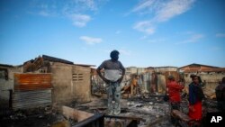 Residentes miran alrededor de las casas dañadas cuando un camión de gasolina volcó y explotó en Cabo Haitiano, Haití, el martes 14 de diciembre de 2021.