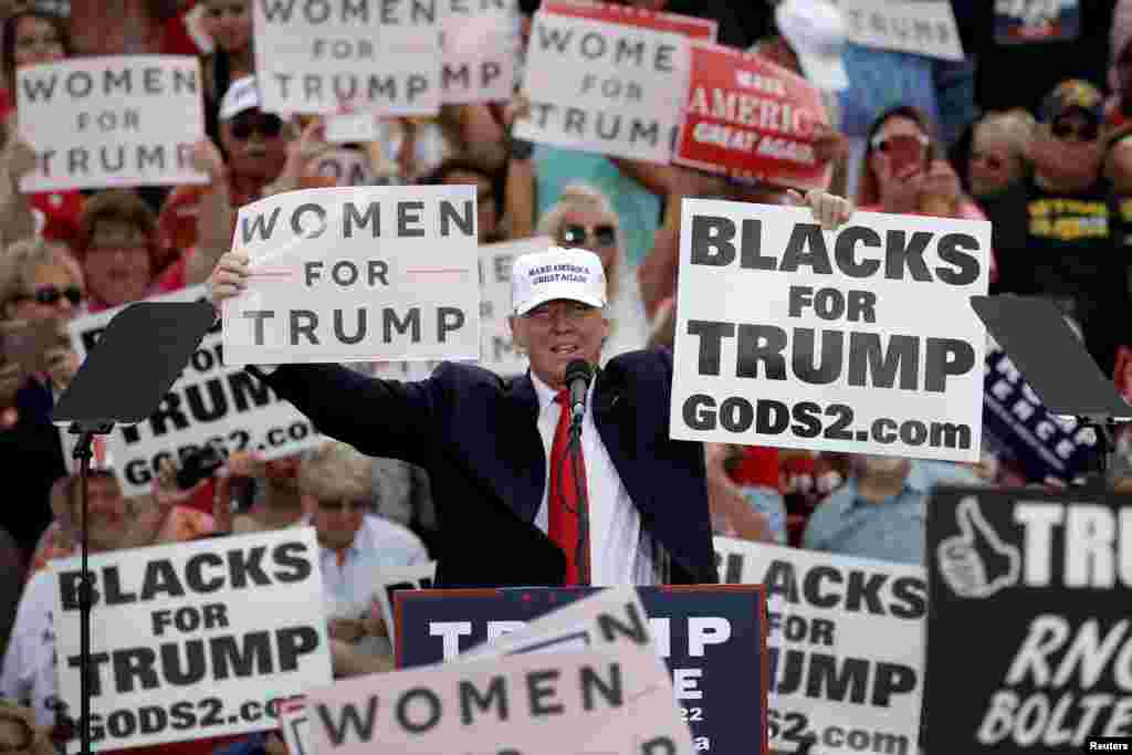 Capres partai Republik Donald Trump bersama pendukungnya memegang banner tulisan kampanye pada akhir kampanye di Lakeland, Florida, AS.