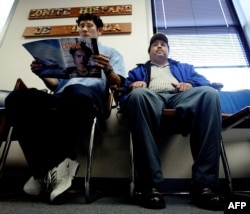 Un ciudadano salvadoreño, a la izquierda, acompañado por un amigo (derecha), espera en el vestíbulo del Comité Hispano de Virginia, en Falls Church, Virginia, el 11 de noviembre de 2002, para obtener ayuda con su documentación de inmigración de EE.UU. para extender su Estado de Protección Temporal (TPS).