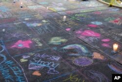 Una acera pintada con mensajes de tiza en Odessa, Texas, en el lugar donde se realizó un servicio funeral por las víctimas de un tiroteo la víspera. AP/Sue Ogrocki.