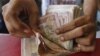 A grocery shop owner counts rupees notes in the western Indian city of Ahmedabad, May 23, 2012.