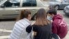 Tres jóvenes revisan sus teléfonos celulares en una plaza de Caracas