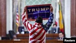 ARCHIVO - Un manifestante sostiene un cartel dea favor del presidente electo Donald Trump mientras el Concejo Municipal de Los Ángeles se reúne para considerar la adopción de una ordenanza de "Ciudad Santuario" en Los Ángeles, California, el 19 de noviembre de 2024.