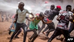 Supporters of Ugandan musician turned politician Robert Kyagulanyi, commonly known as Bobi Wine, run away from a water cannon as they gather at Busabala, where he was planning to hold a news conference, April 22, 2019. 