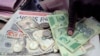 FILE - A man counts Zimbabwean dollar notes and coins and U.S. dollar notes on the streets of Harare, June 25, 2019. 