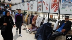 Algerians walk past electoral posters in Algiers, Wednesday, May 9, 2012.