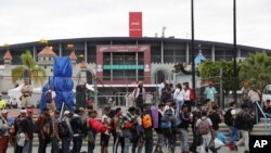 Migrantes hacen fila para ingresar al Auditorio Benito Juárez, en Guadalajara, México.