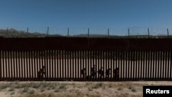 Una vista de un dron muestra a migrantes solicitantes de asilo mientras caminan a lo largo del muro fronterizo tras cruzar la frontera hacia los EEUU, en Jacumba Hot Springs, California, visto desde México, el 16 de mayo de 2024.