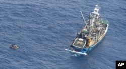 This photo released by the New Zealand Defence Force shows a wooden dinghy, left, carrying seven survivors from a missing ferry and a fishing boat in the Pacific Ocean, Jan. 28, 2018.