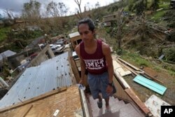 José Colón sube las escaleras de la destruida casa de un amigo luego del huracán María en Aibonito, Puerto Rico. Sept. 25, 2017.