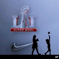 Fans walk past a sign at the NFL Experience ahead of the NFL Super Bowl 51 football game, Feb. 3, 2017, in Houston, Texas.
