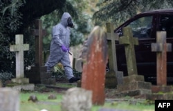 A man in a hazmat suit walks by London Road Cemetery in Salisbury, England, near the home of Sergei Skripal, who, along with his daughter Yulia were poisoned with Novichok on March 4, 2018.