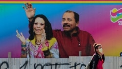 Una mujer lleva una mascarilla protectora en Managua (Nicaragua), como medida de precaución para frenar la propagación del coronavirus, mientras pasea frente a un mural del presidente Daniel Ortega y la vicepresidenta Rosario Murillo.