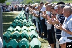 FILE - Bosnian Muslims pray in front of coffins during a reburial ceremony for dozens of newly identified victims of the 1995 massacre, at the memorial center of Potocari near Srebrenica, 150 km northeast of Sarajevo, Bosnia, July 11, 2017.