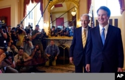 El candidato a la Corte Suprema Brett Kavanaugh, a la derecha, y el senador Chuck Grassley, republicano por Iowa, segundo desde la derecha, caminan frente a la prensa después de posar para fotógrafos en el Capitolio, en Washington, el 10 de julio de 2018.
