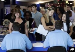 Los solicitantes de empleo hablan con representantes de Aldi en una feria de trabajo.