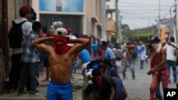 Un manifestante usa una camiseta como una máscara improvisada para protegerse del gas lacrimógeno durante enfrentamientos con la policía y partidarios del gobierno en el distrito Monimbo de Masaya, Nicaragua, el sábado, 12 de mayo, de 2018.