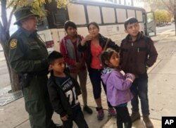 Archivo - Una familia de migrantes de Centro América espera frente a un refugio en El Paso, Texas, el 29 de noviembre, de 2018.