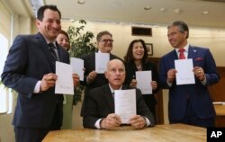 Governor Jerry Brown holds a copy of a bill to end bail that he signed in Sacramento, Calif., Aug. 28, 2018.