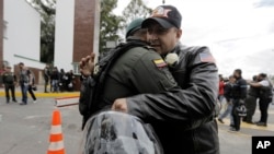 Un hombre abraza a un oficial de policía, afuera de la Academia de Policía General Francisco de Paula Santander, un día después de que explotara un coche bomba en el lugar, en Bogotá.