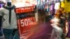 Compradores pasan junto a un cartel que promueve las ventas del Viernes Negro en el centro comercial Sambil en Caracas, el 29 de noviembre de 2019.