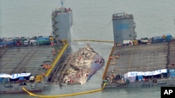 Workers prepare to lift the sunken Sewol ferry (center) in waters off Jindo, South Korea, March 23, 2017. The 6,800-ton South Korean ferry emerged from the water Thursday, nearly three years after it capsized and sank into violent seas off the country's southwestern coast.