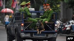 FILE - Policemen sit in the back of a truck in Hanoi, Vietnam, March 1, 2019.