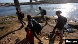 Migrantes caminan a lo largo de las orillas del río Grande antes de cruzar en un intento de buscar asilo en Estados Unidos, visto desde Piedras Negras, México, el 29 de septiembre de 2023. 