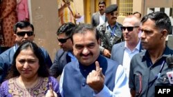 Gautam Adani, kepala konglomerat India Adani Group dan istrinya Priti Adani menunjukkan jari bertinta usai menjalankan hak pilih di Ahbedabad, 7 Mei 2024. (Foto: Sam Panthaky/AFP)