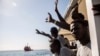 Migrants aboard the Open Arms aid boat, of Proactiva Open Arms Spanish NGO, react as the ship approaches the port of Barcelona, Spain, Wednesday, July 4, 2018. The aid boat sailed to Spain with 60 migrants rescued on Saturday in waters near Libya, after it was rejected by both Italy and Malta.