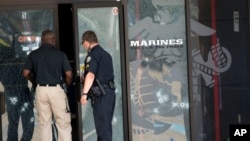 Agentes policiales entran al Centro de Carrera de las Fuerzas Armadas a través de la puerta impactada por las balas, en Chattanooga, Tennessee, este jueves 16 de julio de 2015.
