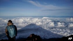 Bayangan Gunung Fuji terpantul di awan yang berawak di bawah puncak gunung, 27 Agustus 2019, di Jepang. Polisi mengtakan tiga mayat pendaki ditemukan di Gunung Fuji pada Kamis, 27 Juni 2024. (/foto: Jae C. Hong)