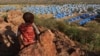 FILE - A boy sits atop a hill overlooking a refugee camp near the Chad-Sudan border, November 9, 2023. 