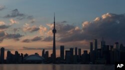 FILE - The sun sets on the Toronto skyline, July 10, 2015. 