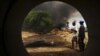 Oil workers, seen through a pipe, look on at the scene of an oil pipeline fire in Dadabili, Niger state, April 2, 2011.