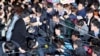 Choi Soon-sil, center left wearing black hat, a cult leader's daughter with a decades-long connection to President Park Geun-hye, is surrounded by prosecutor's officers and media at the Seoul Central District Prosecutors' Office in Seoul, South Korea, Oct. 31, 2016.