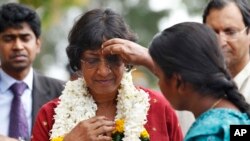 FILE - A Sri Lankan ethnic Tamil girl applies vermillion on the forehead of U.N. High Commissioner for Human Rights Navi Pillay, in red, as she welcomes her at a vocational training center in Kilinochchi, Sri Lanka, Aug. 27, 2013.