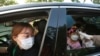 A young girl has her temperature checked as she arrives to watch a drive-in concert at the Gyeongbok Palace parking lot in Seoul, South Korea, July 17, 2020. 