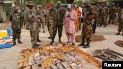 Military officials stand near ammunitions seized from suspected members of Hezbollah after a raid of a building in Kano, Nigeria, May 30, 2013.