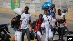 Vecinos del barrio de Solino, desplazados de sus hogares debido a los enfrentamientos entre pandillas armadas, buscan refugio mientras caminan por una calle de la comunidad de Carrefour de Puerto Príncipe, Haití, jueves 18 de enero de 2024.