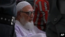Bangladesh's Islamic party Jamaat-e-Islami former chief Ghulam Azam, on wheelchair, is escorted by security people to a court in Dhaka, July 15, 2013. 