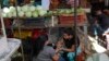 Una vendedora venezolana hace manicura a otra mujer mientras espera por clientes en el mercado de Las Pulgas, en Maracaibo, el 29 de diciembre de 2023.