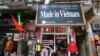 FILE - Vendors sit outside a shop selling clothes in Hanoi, Vietnam, October 3, 2014.
