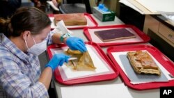 Sue Donovan, conservator for Special Collections at the University of Virginia, works on an envelope from a time capsule removed from the pedestal that once held a statue of Confederate General Robert E. Lee on Dec. 22, 2021, in Richmond, Va. 