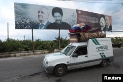 Un vehículo con pertenencias pasa junto a una imagen del presidente del Parlamento libanés, Nabih Berri, y del imán Musa al-Sadr, en Tiro, después de que entrara en vigor el miércoles 27 de noviembre de 2024 un alto el fuego entre Israel y el grupo Hezbolá.