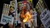A man burns banners being held by protesters during an anti-North Korea rally in central Seoul, South Korea, Feb. 11, 2016.